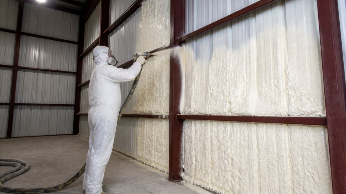 Contractor applying spray foam steel building insulation to interior metal walls